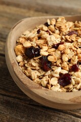 Tasty granola with dried fruits in bowl on wooden table, closeup