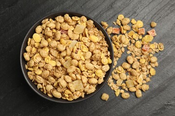 Tasty granola with dried fruits in bowl on black table, top view