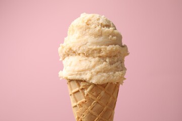 Tasty ice cream in waffle cone on color background, closeup