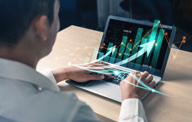 A businessman analyzes financial data on a laptop, showcasing stock market graphs with rising arrows, symbolizing economic growth in a modern office environment. Scalp