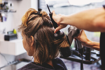 Woman receiving professional haircut and styling in beauty salon by hairdresser. Hair care ritual, beauty treatment and pampering concept