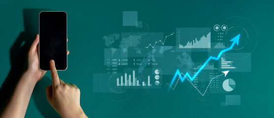 A hand operates a smartphone featuring diverse business analytics and growth data visualizations against a dark green backdrop. Ideal for themes of technology and analysis. Scalp