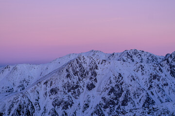 Snowy mountains under a pink sky during sunset in a high-altitude location