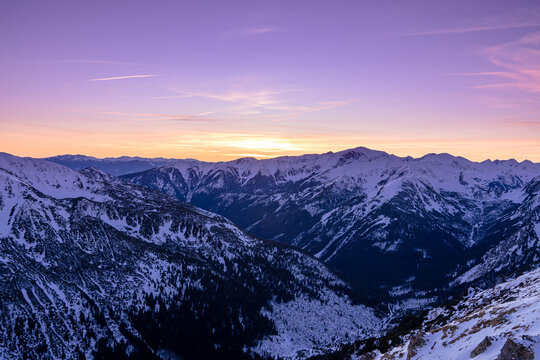 Sunset over snowy mountains in the winter sky with peaks visible in the distance - Powered by Adobe