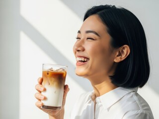 A young asian woman smiling and holding a glass of iced coffee with milk on a sunny day