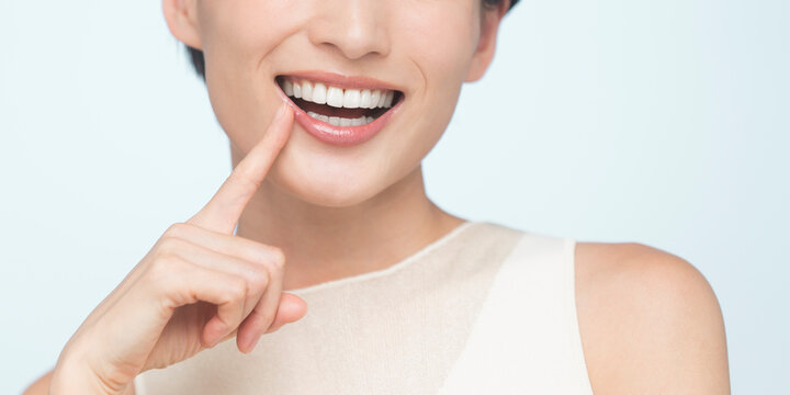 口元を指さす笑顔の女性