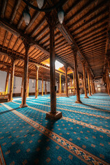 Esrefoglu Mosque interior in Konya, Turkiye, showcasing carved wooden pillars, colorful tile motifs, rich patterns, and finely detailed Islamic craftsmanship.