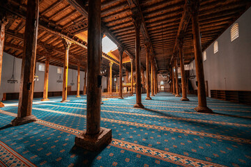 Esrefoglu Mosque interior in Konya, Turkiye, showcasing carved wooden pillars, colorful tile motifs, rich patterns, and finely detailed Islamic craftsmanship.
