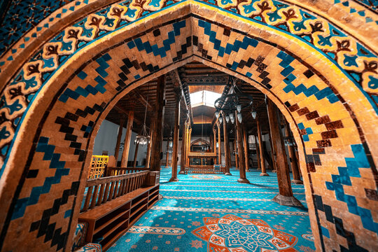 Esrefoglu Mosque interior in Konya, Turkiye, featuring ornate wooden pillars, intricate Islamic patterns, vibrant colors, and historic craftsmanship.