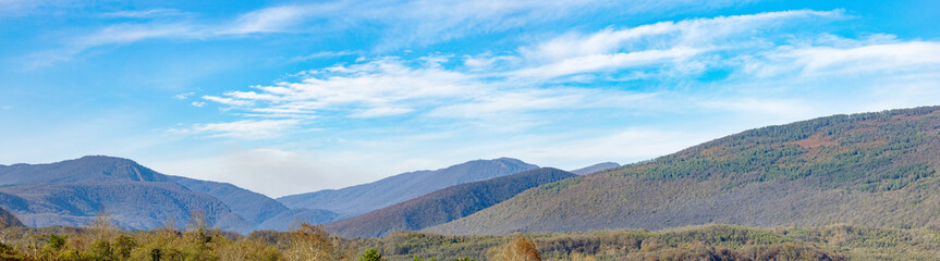 Panorama of the mountains. Amazing morning fog in the mountains. Beautiful sunrise light shines on the red beech forest. Drone panorama. Landscape photography.