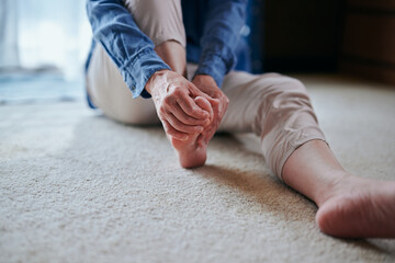 足をマッサージする冷え性のシニア女性