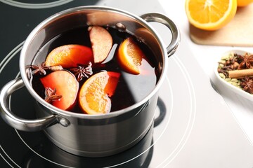 Tasty mulled wine cooking in pot on stove, closeup