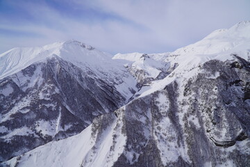 A snow-covered mountain range in the Caucasus region near the Gudauri ski resort. Georgia. Snow-capped mountain peaks and steep slopes.