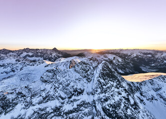 Aerial view of snow-covered mountains at sunset in a remote region