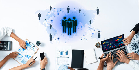 A dynamic business meeting featuring diverse professionals analyzing data and charts on digital devices, set against an abstract global map backdrop, emphasizing collaboration and strategy. Trope