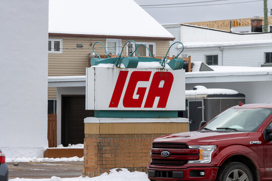 Canada, Quebec, 15 November 2025 : Red pickup truck parked near snowy grocery store IGA sign