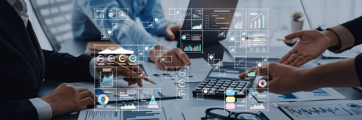 A team of business professionals collaborates on data analysis, utilizing digital charts and graphs on a laptop during an important meeting at the conference table. Trope
