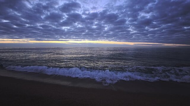 Calm Morning Waves Beneath Patterned Cloud Sky at Dawn in Arenys Coast