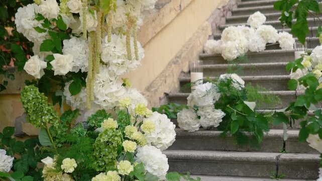 A beautiful wedding arch with white flowers and festive decor in an old Italian courtyard with architectural features. A symbol of romance and love on the bride and groom's special day