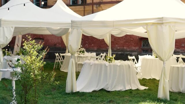A very beautiful and stylish banquet table with a tent outdoors. Wedding decor and floral arrangements before the ceremony and celebration