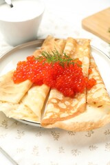 Tasty crepes with red caviar, sour cream and dill on table, closeup
