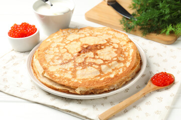 Tasty crepes with red caviar, sour cream and dill on white wooden table, closeup
