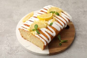 Delicious lemon cake with glaze, fresh fruit slices and mint on gray textured table, closeup