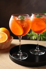 Refreshing spritzer cocktail with mint and oranges on wooden table