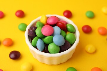 Delicious colorful candies on yellow background, closeup