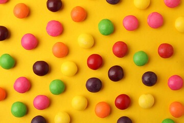 Delicious colorful candies on yellow background, flat lay