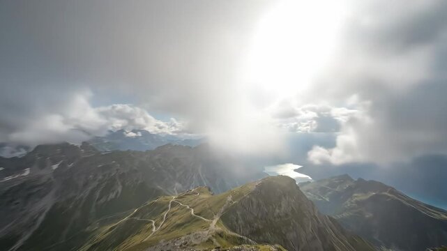 Clouds forming a heart shape in the sky above a winding mountain range, revealing a shimmering lake and sun rays breaking through with atmospheric light