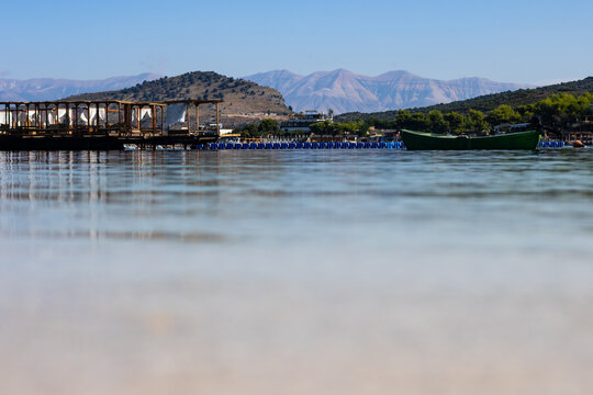 Tranquil sea surface with distant beach facilities, mountains and sky at Ksamil, Albania. Copyspace for text