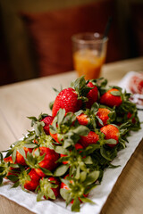Close-up of fresh strawberries on a white plate with a soft café background. Warm tones, shallow focus, and natural light create a relaxed breakfast and lifestyle food mood.