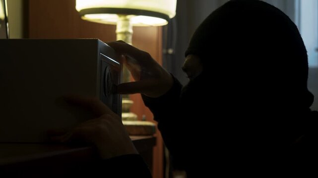 Close up of thief frantically grabbing bundles of cash from open safe after alarm goes off, then rushing out of room to escape before police arrive.