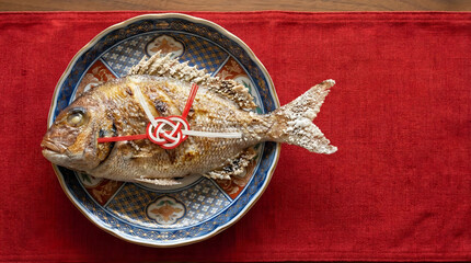 Salt-grilled whole fish (Tai or Snapper) with Mizuhiki knot on a blue ceramic plate.