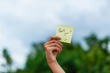 Thank you note held in hand outdoor setting positive gesture nature background close-up shot