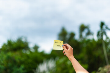 Hand holding welcome note in lush nature setting outdoor event serene environment close-up view