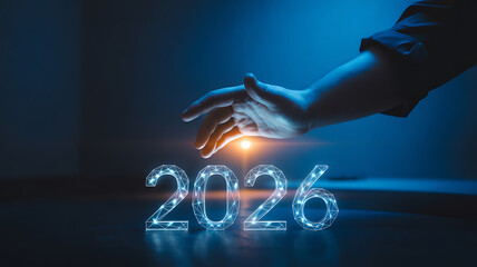 Hand reaching for glowing digital number 2026 representing future technology and success in the new year
