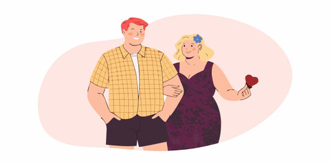 A couple stands closely together a woman holding a red heart shape