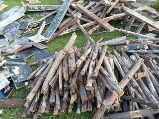 Pile of firewood stacked on green grass outdoors