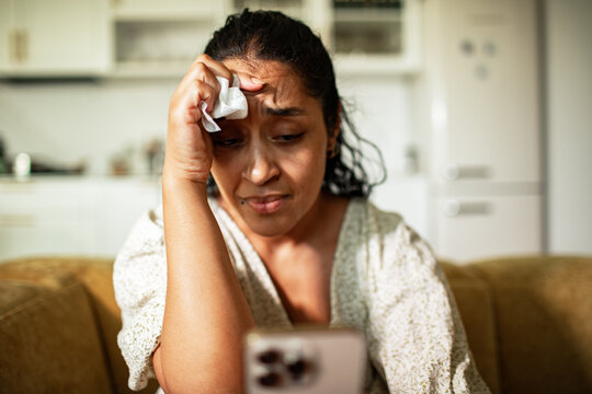 Young adult woman worried while reading phone at home