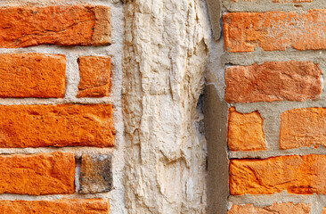 Close-up of weathered red brick wall with exposed mortar