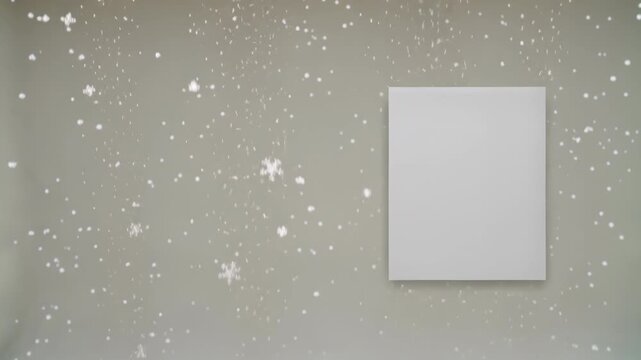 Blank canvas on a neutral gray wall with delicate falling snowflakes, creating a serene winter atmosphere. Soft lighting enhances the gentle snowfall effect, perfect for seasonal art displays.