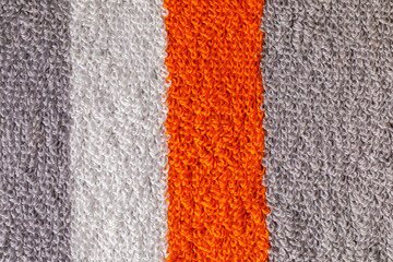 Fototapeta premium A close-up shot of a textured gray towel, with orange and white strips showcasing its fluffy and soft fabric loops. Horizontal photo