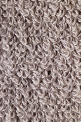 A close-up shot of a textured gray towel, showcasing its fluffy and soft fabric loops. Vertical photo