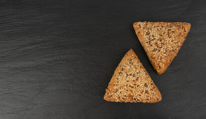 Triangular bun closeup. Wheat bread with sesame and flax seeds, healthy whole grain bakery