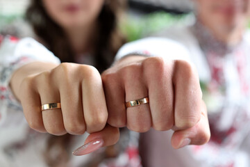 The hands of the newlyweds with wedding rings are clenched into fists.