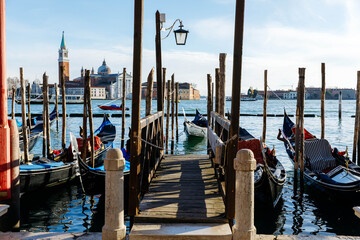 Venice, Italy - December 05, 2025: Scenic view of gondolas lined up at a wooden dock in Venice,...