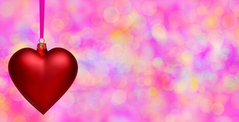 Poczt&oacute;wka walentynkowa - czerwona bombka choinkowa w kształcie serca na tle r&oacute;żowych i purpurowych rozmyć światła typu bokeh