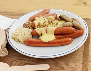 濃厚チーズソースがかかった数種類のドイツソーセージとザワークラウト
